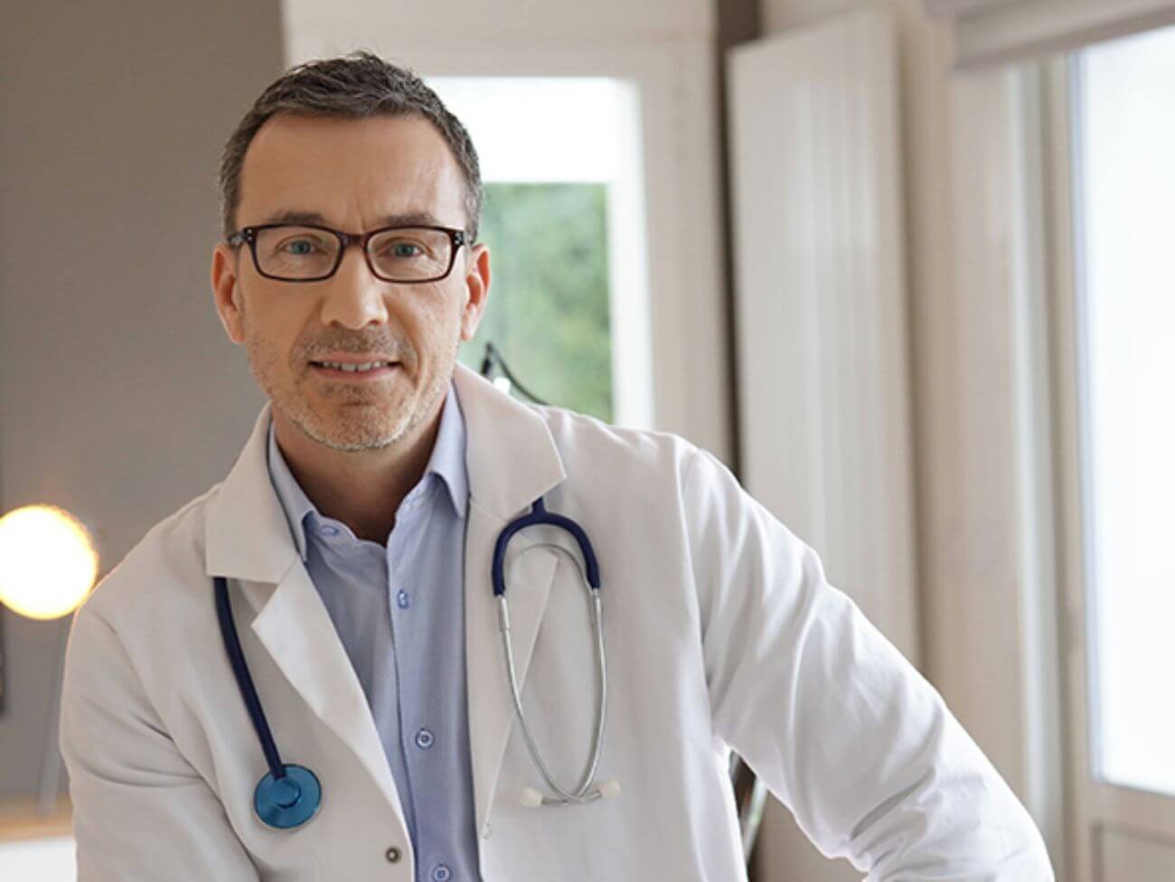 A doctor smiles while looking into the camera.