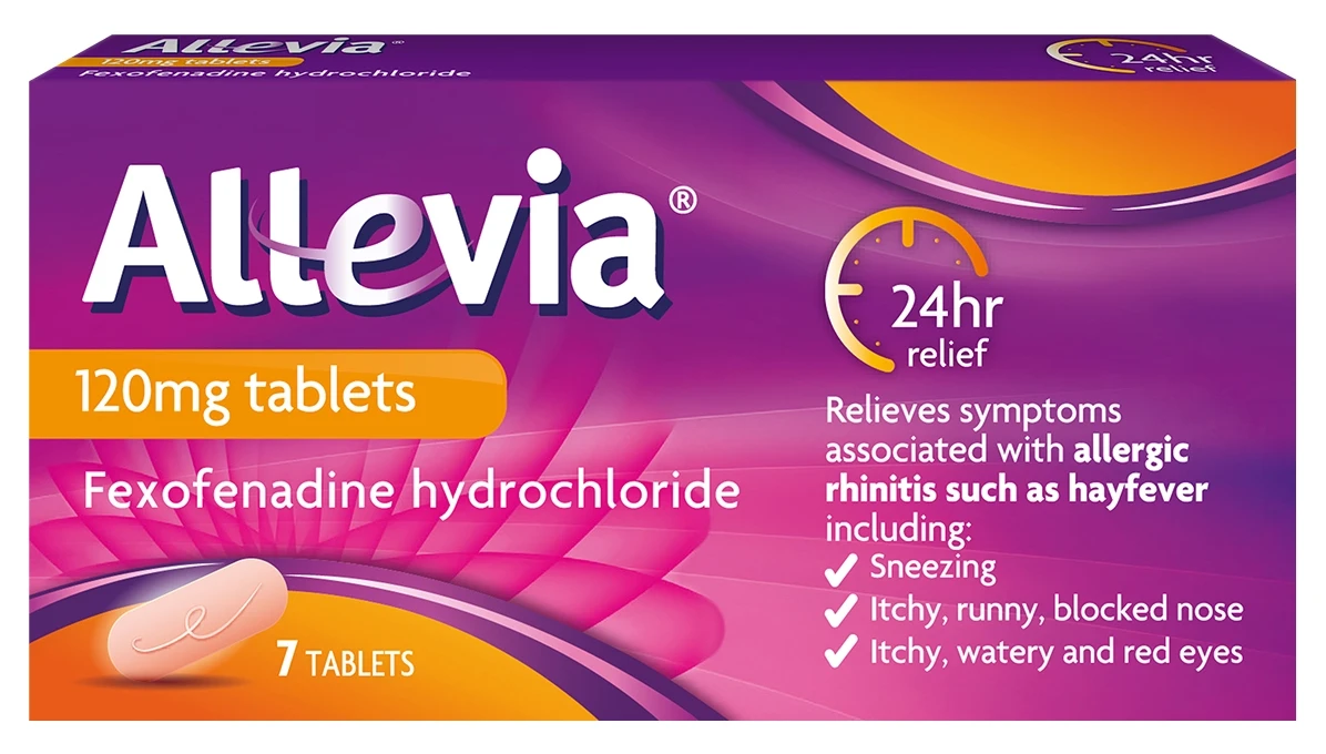 A lady in the pharmacy aisle checking the label of the Allevia Allergy tablet pack.