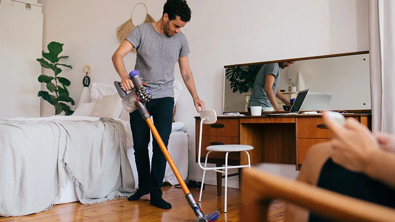 man vaccuming his bedroom