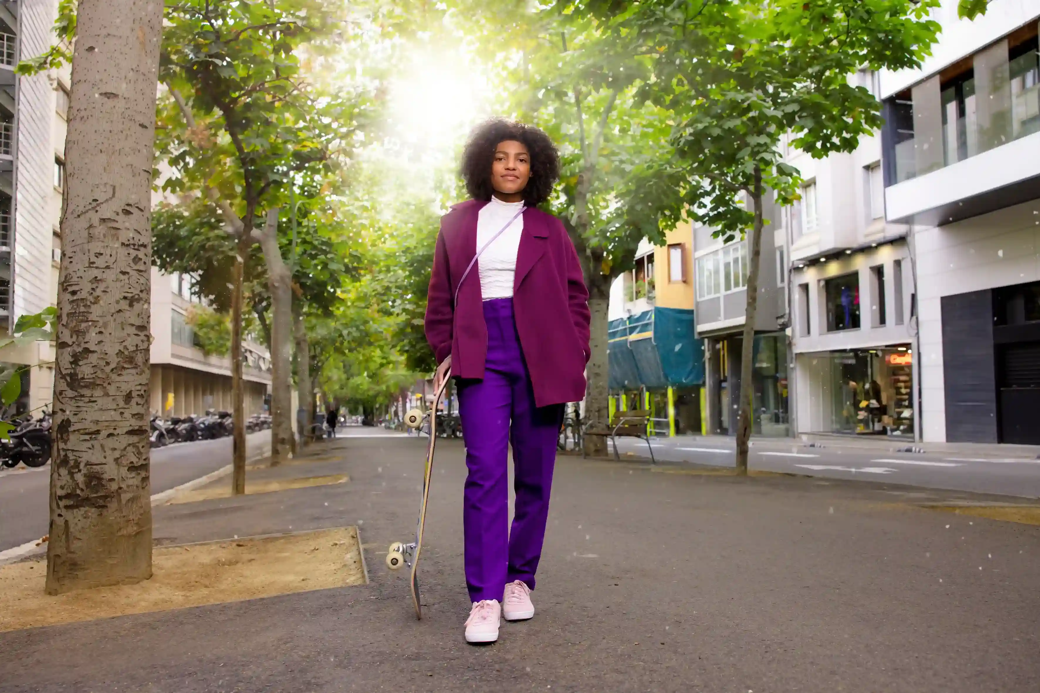A woman confidently standing outside in front of some trees.